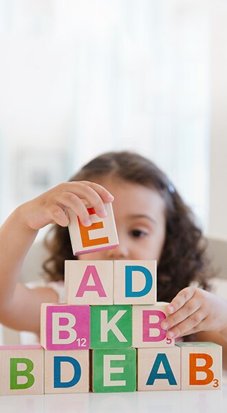 Ein Kind das mit Buchstabenklötze spielt - Un enfant jouant avec des blocs alphabétiques