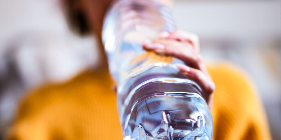 Ein Mann der aus einer Plastikflasche trinkt