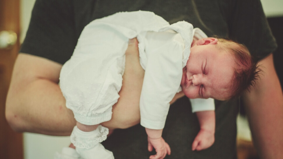 Baby schläft auf dem Arm des Vaters