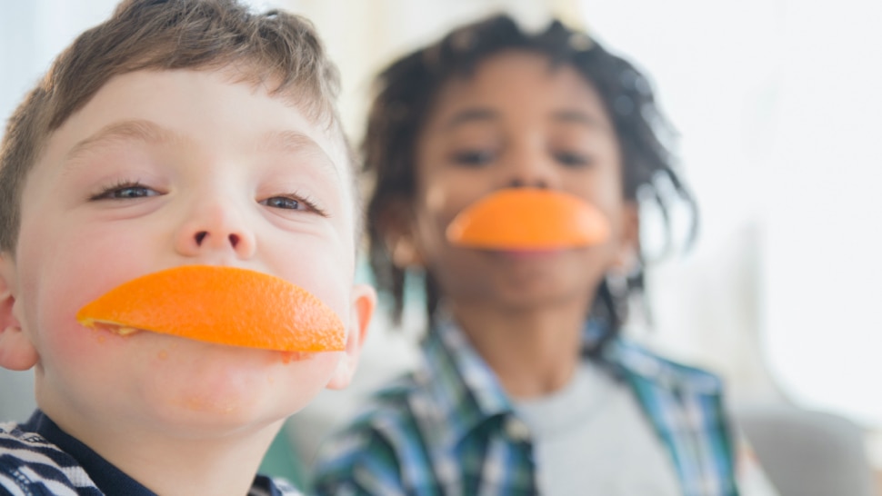 Kinder mit Orange im Mund