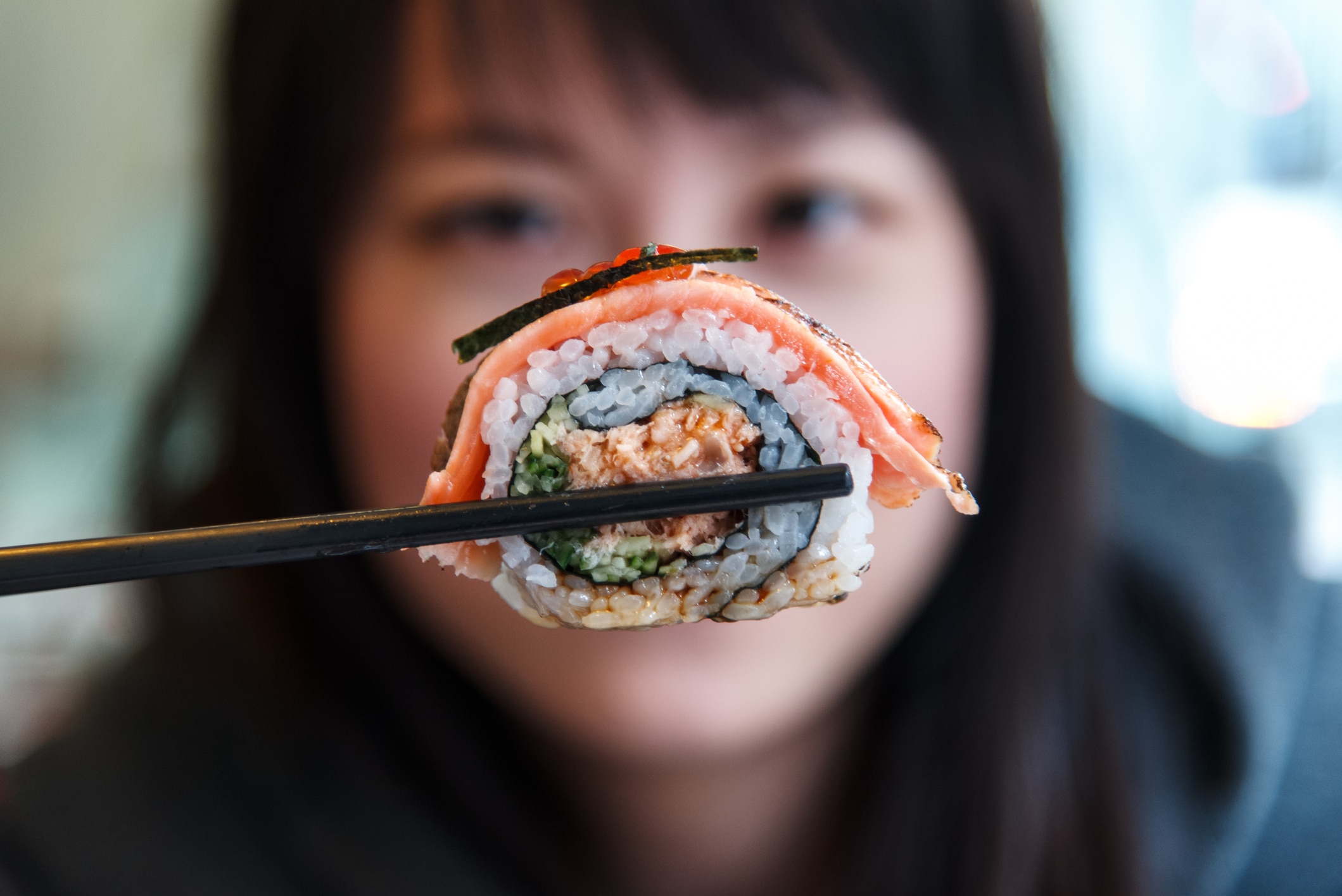 Person showing Sushi roll into camera