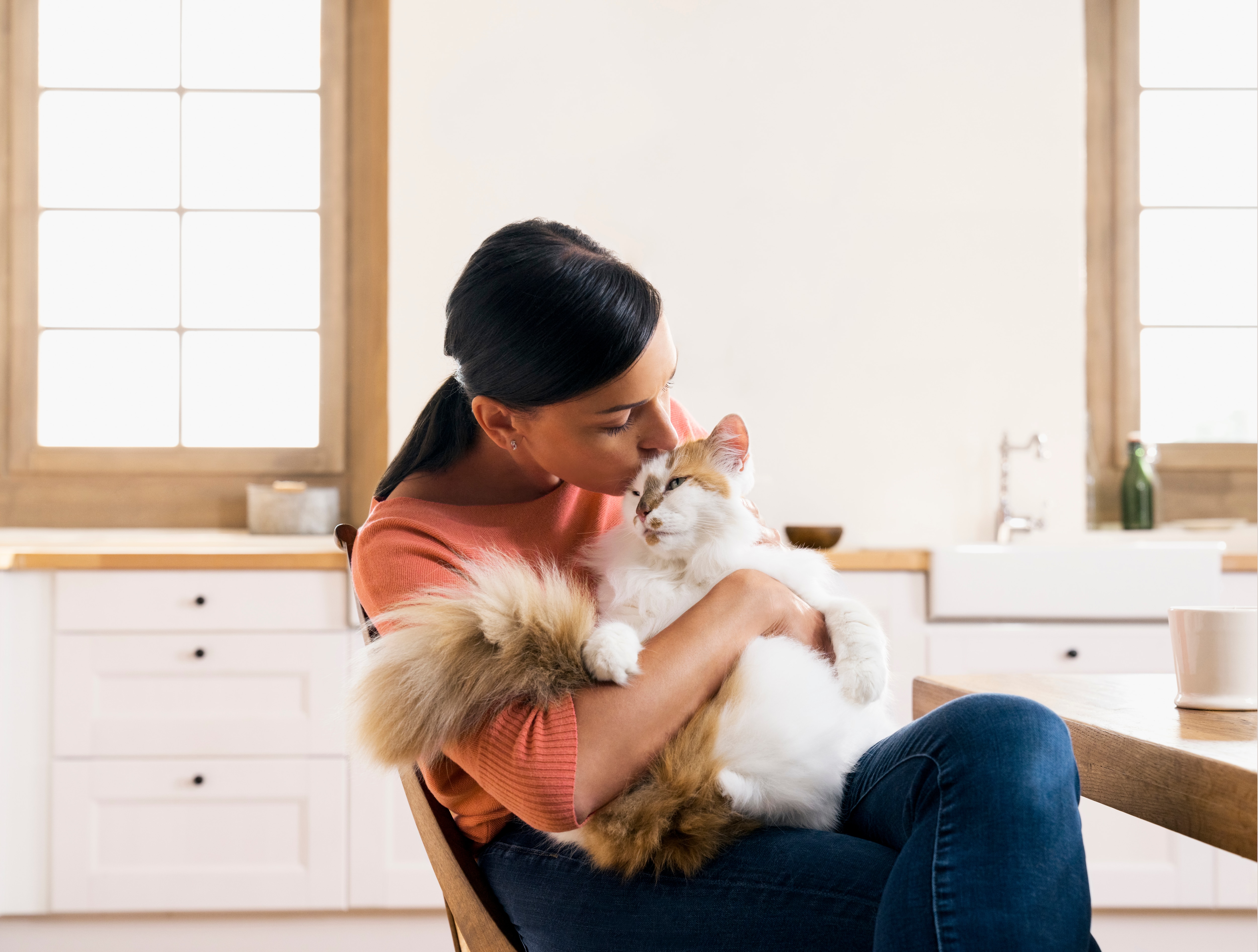 woman cuddling her cat in the kitchen