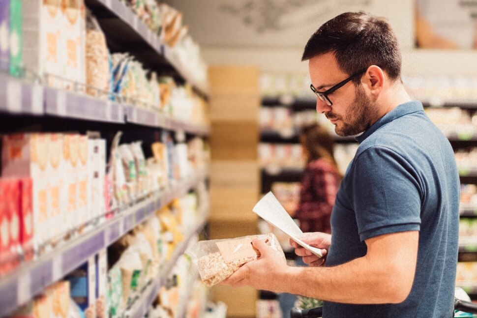 Mann im Supermarkt, der eine Produktverpackung liest