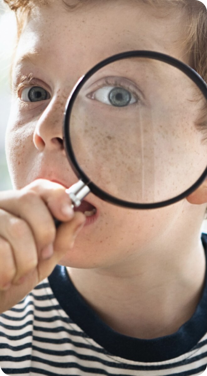 Kind schaut durch eine Lupe