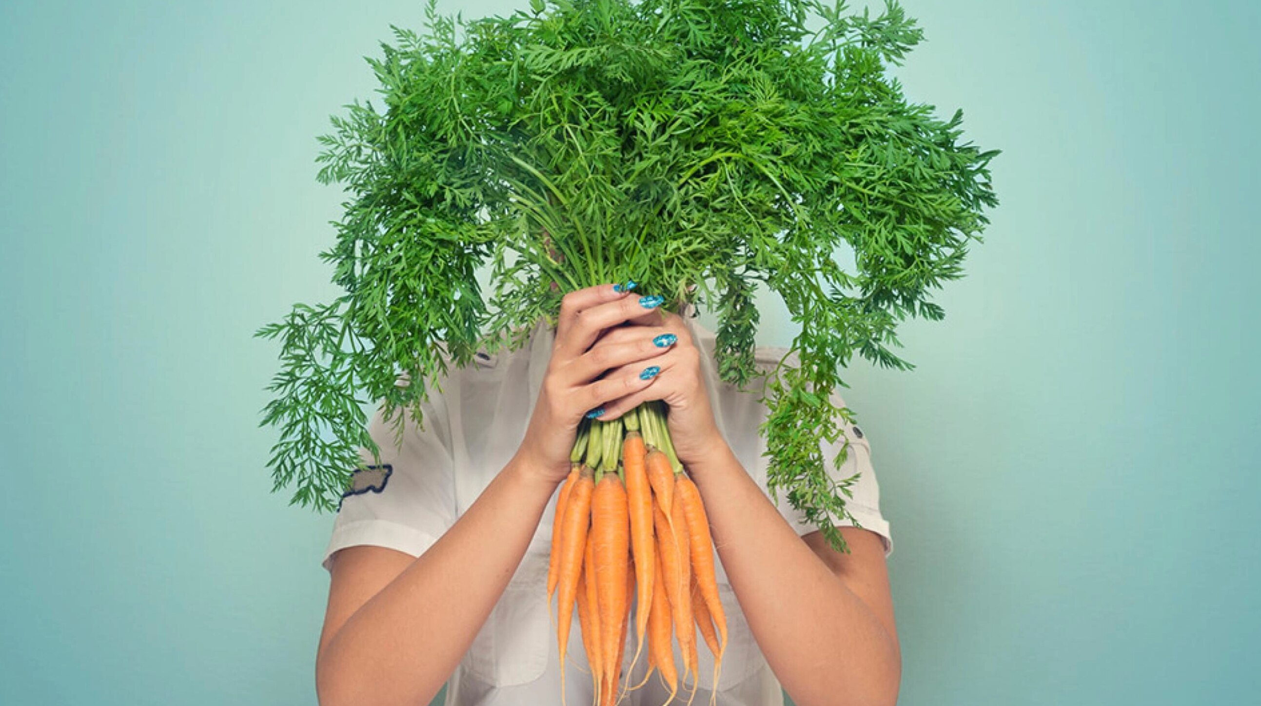 Une femme met des carottes devant son visage