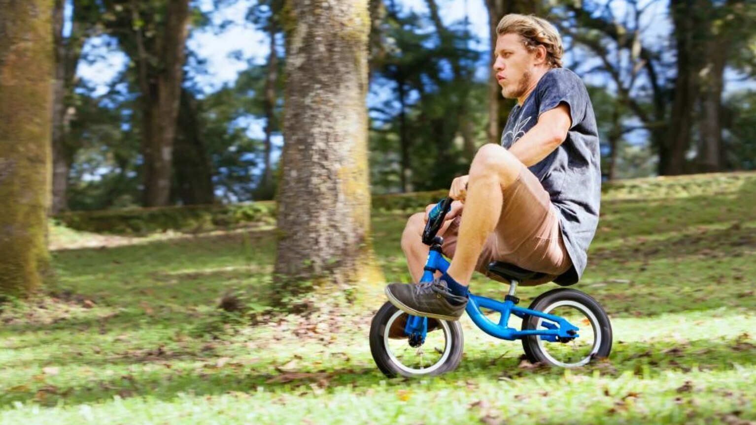 un homme roule avec un vélo d'enfant