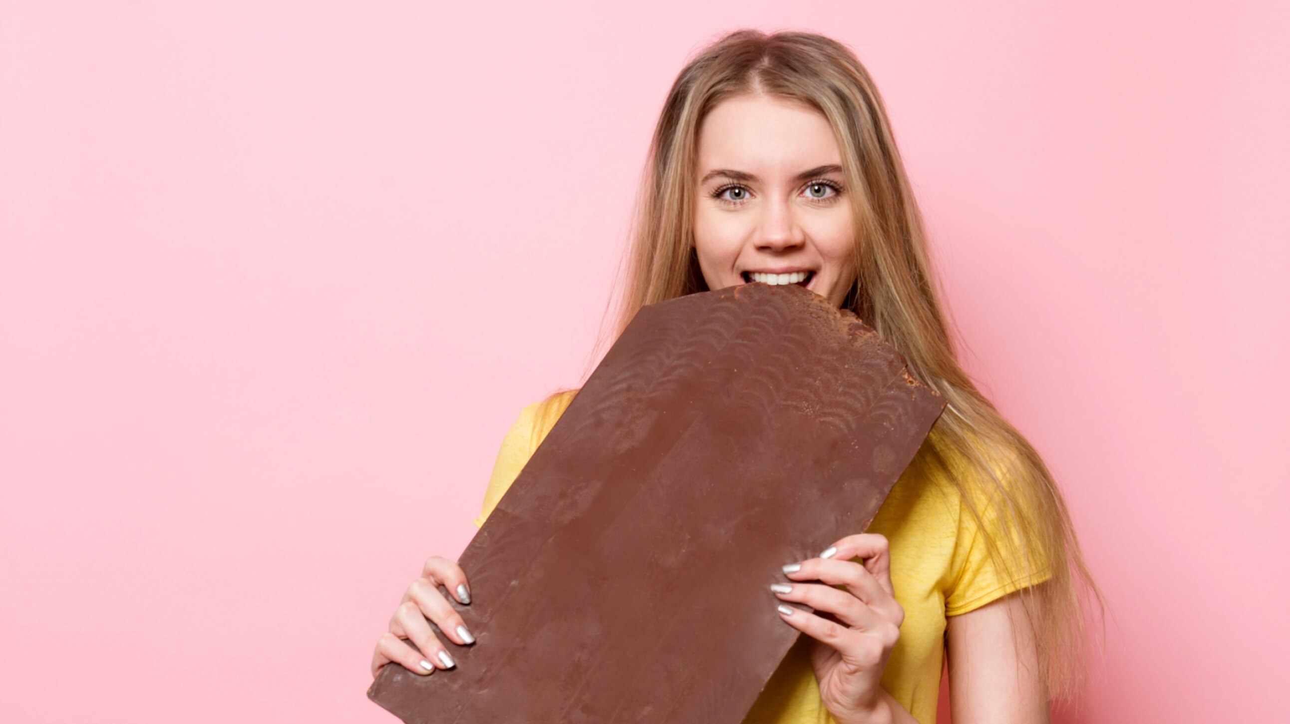 Une femme croque dans un gros chocolat