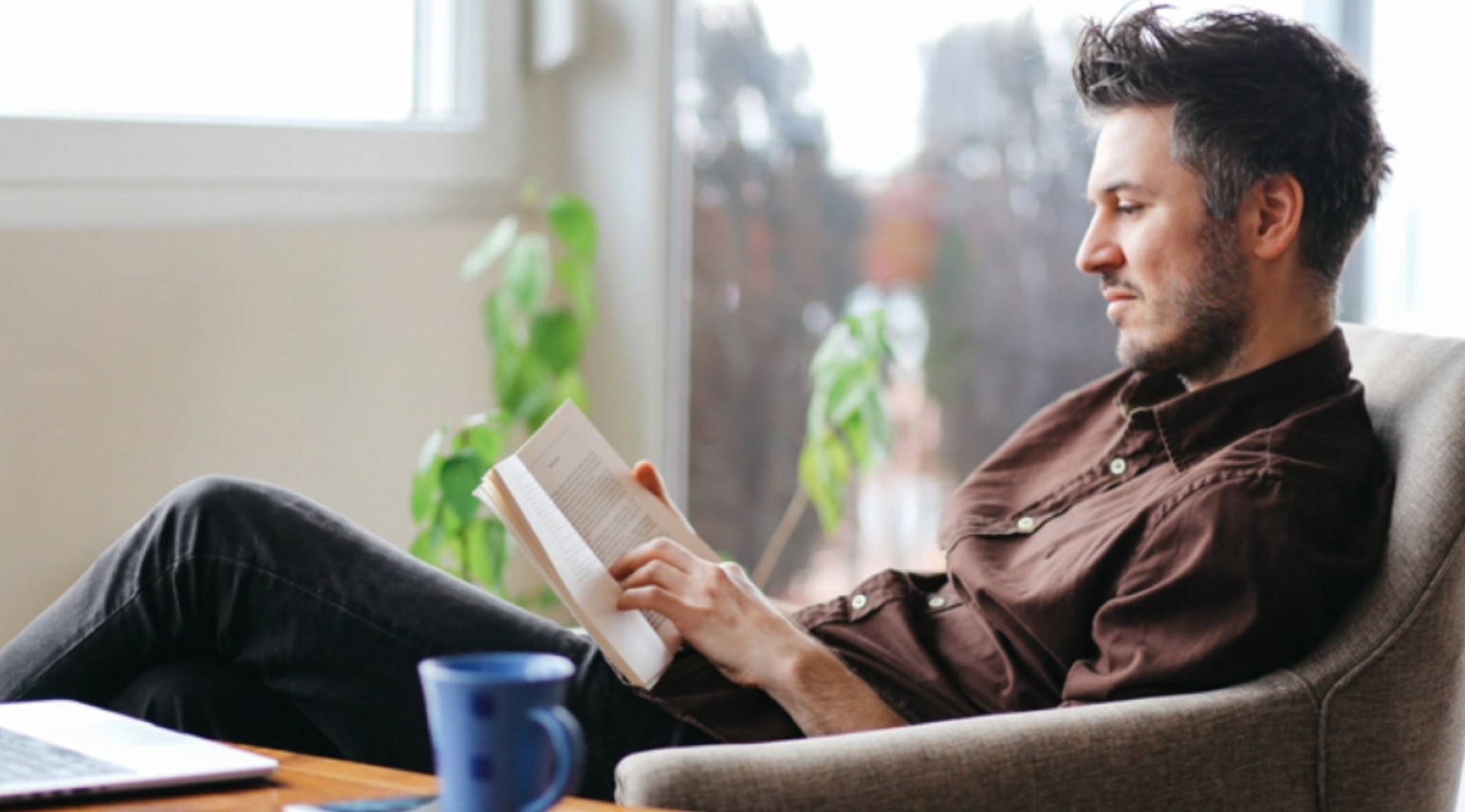 Un homme lit un livre dans son salon