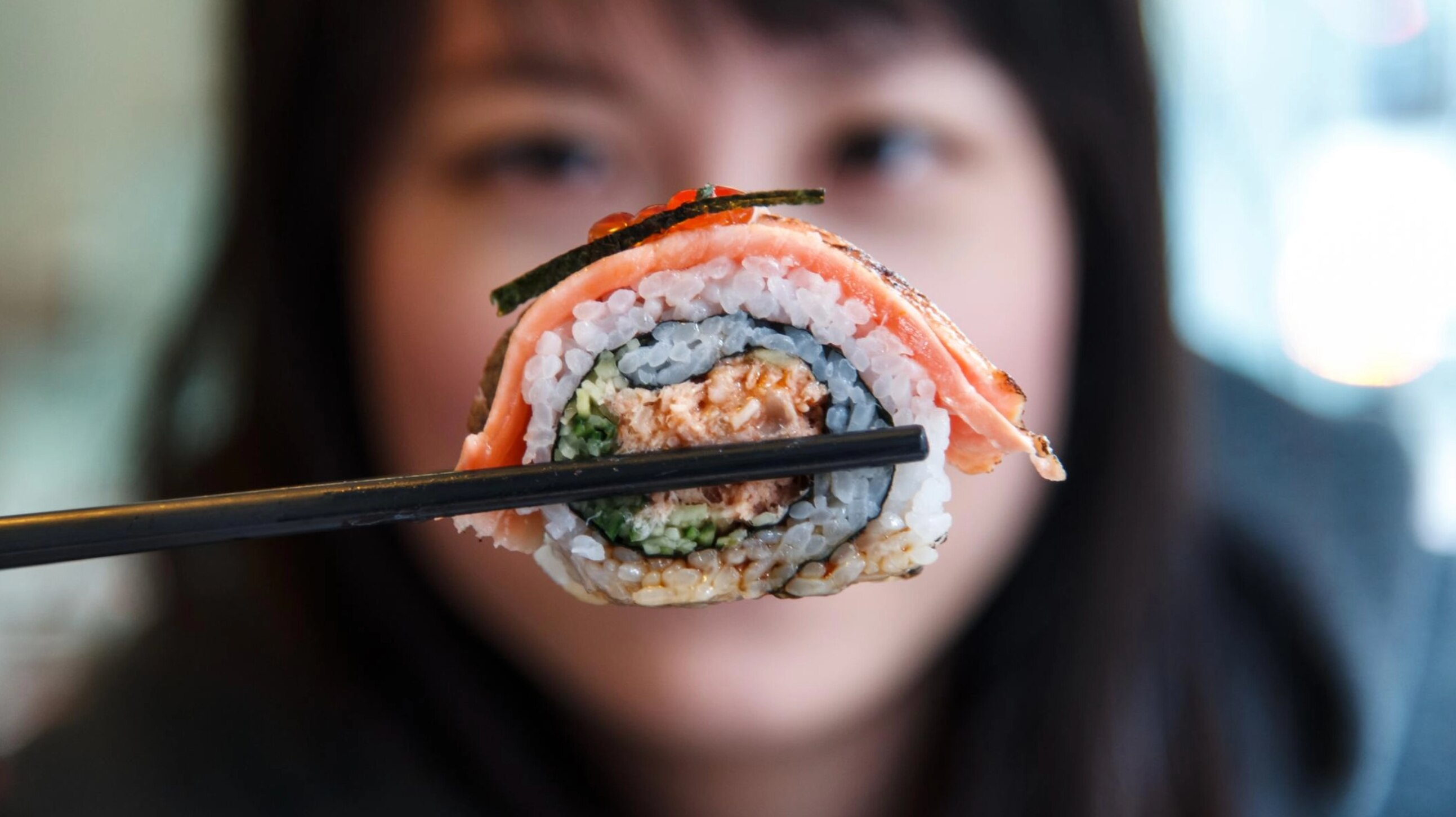 Frau hält Sushi hoch