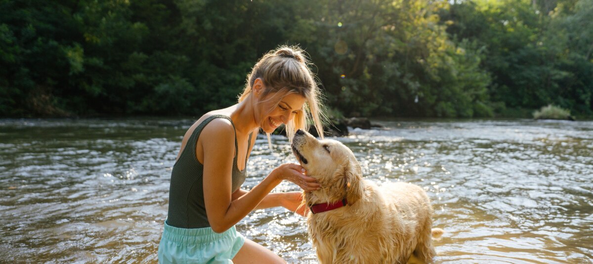Frau mit Hund am Wasser