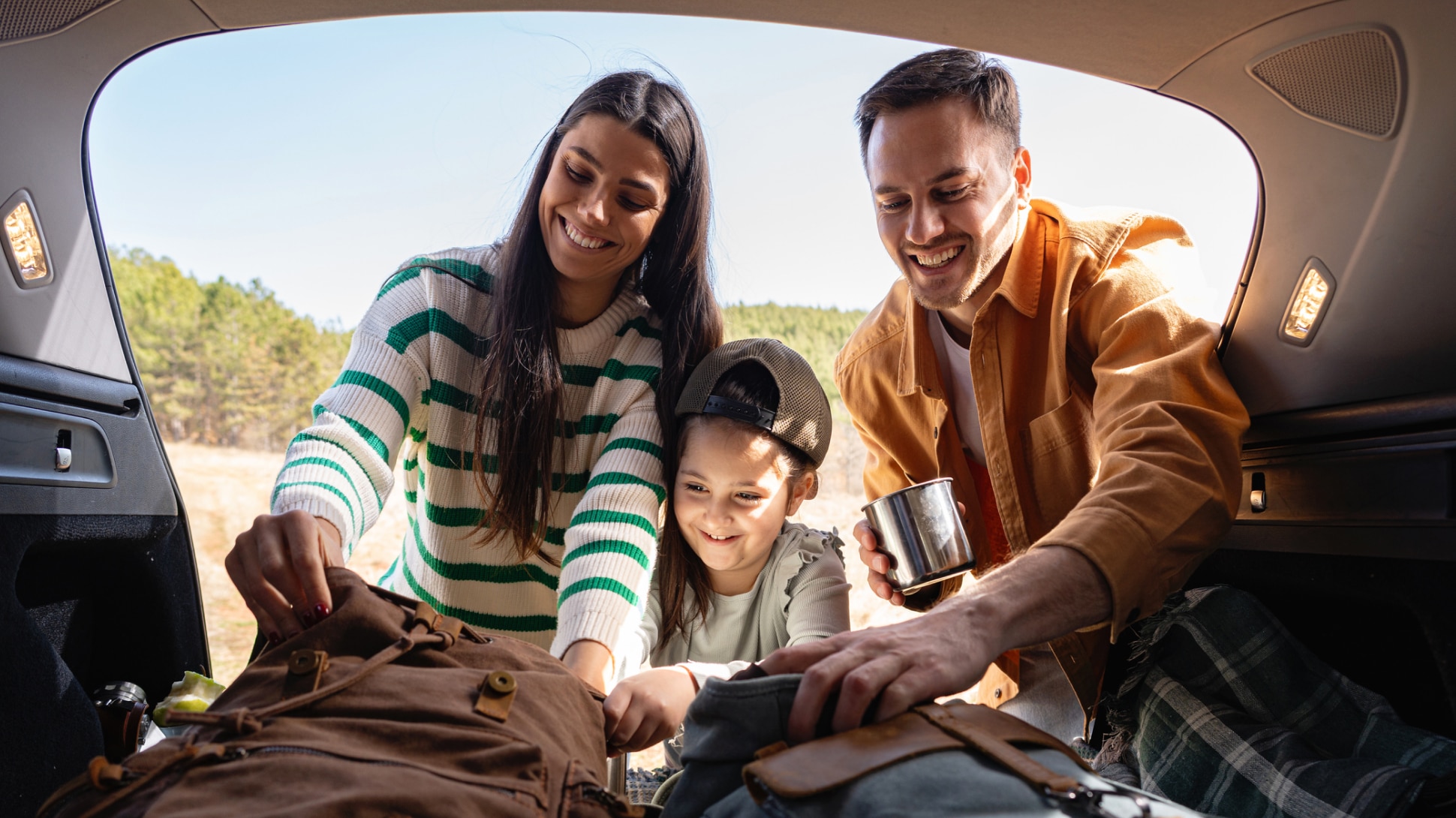 Familie packt Picknick Sachen ins Auto
