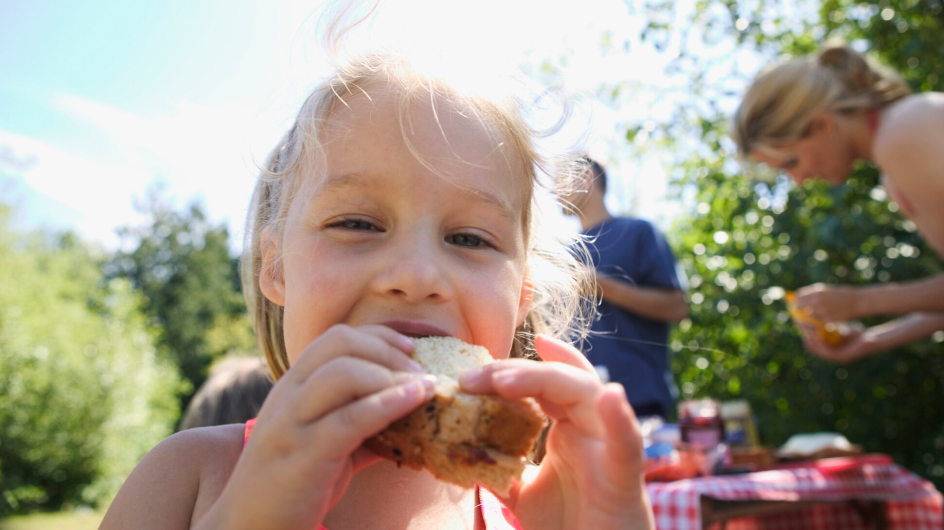 Lachendes Mädchen beisst in ein Sandwich