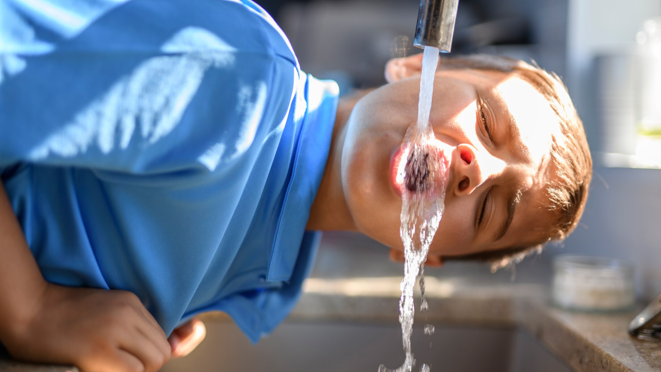 Junge trinkt aus Wasserhahn