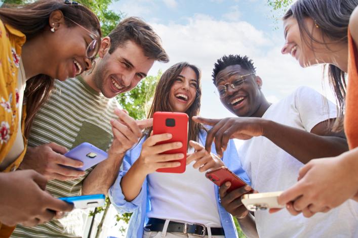 Groupe de jeunes rient en lisant quelque chose sur un smartphone.
