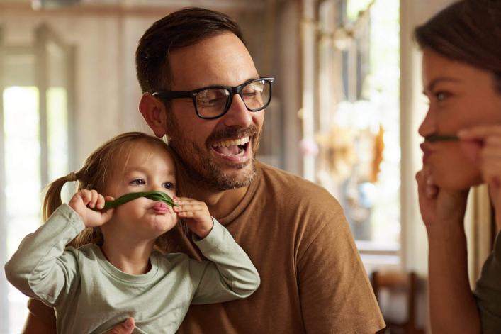 Fröhliche Familie geniesst gemeinsam ein Essen am Tisch und hat dabei richtig Spass