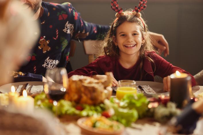 Festlich gekleidetes Mädchen am Esstisch mit Familie 