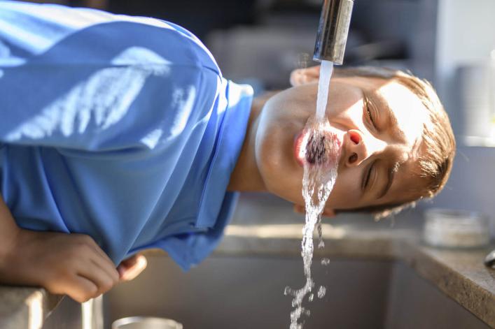 Garçon buvant de l’eau directement du robinet