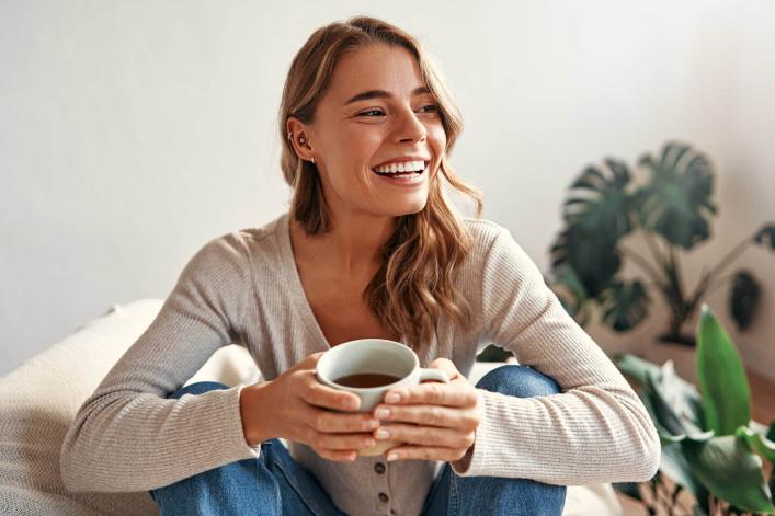 Jeune femme souriante savourant un café dans un café ensoleillé