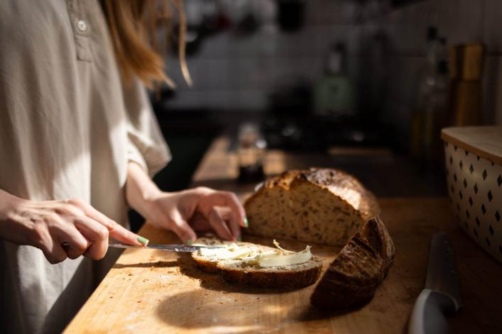 Frau streicht Butter auf Vollkornbrot in der Küche