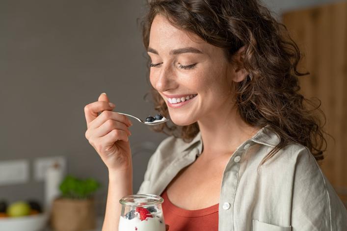 Frau, die zu Hause einen Joghurt mit Beeren geniesst
