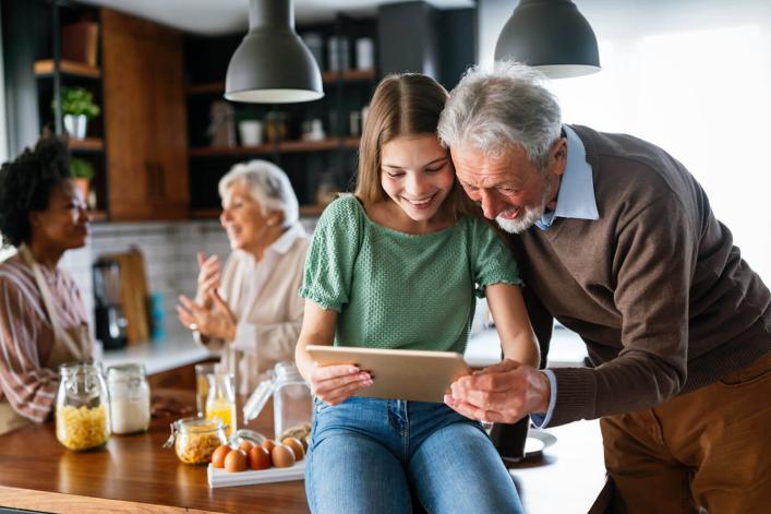 Grossvater und seine Enkelin in der Küche, die Informationen auf ihrem Tablet ansehen