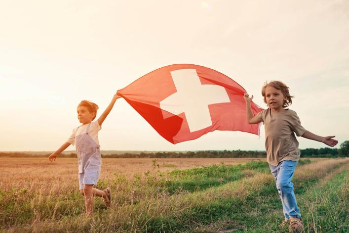 Zwei Jungen rennen und tragen eine Schweizer Fahne zum 1. August