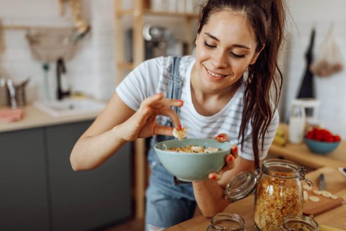Jeune femme goûtant le petit-déjeuner qu'elle vient de préparer, avec un sourire