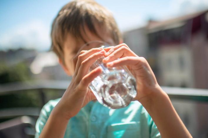 Junge trinkt ein Glas Wasser in der Sommersonne