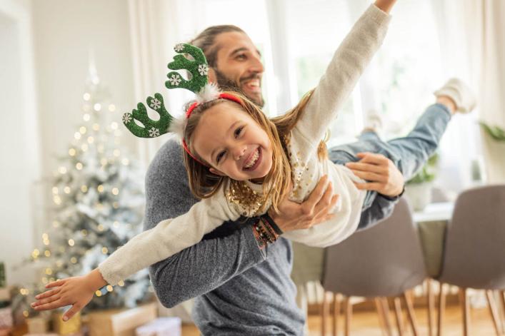 Père jouant avec sa fille à Noël, elle est portée comme un avion