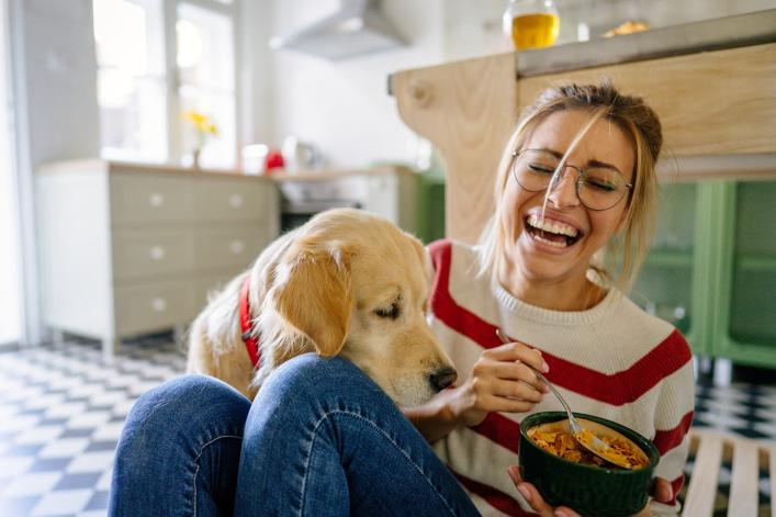 Golden Retriever neben Person mit einer Schüssel in der Küche.