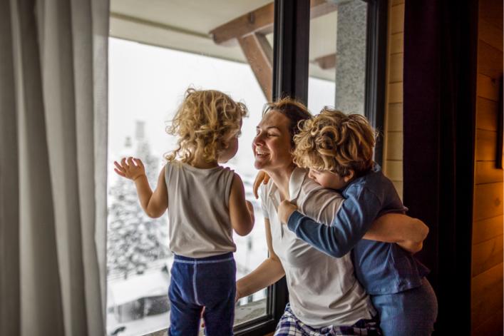 Glückliche Familie schaut im Winter aus dem Fenster 