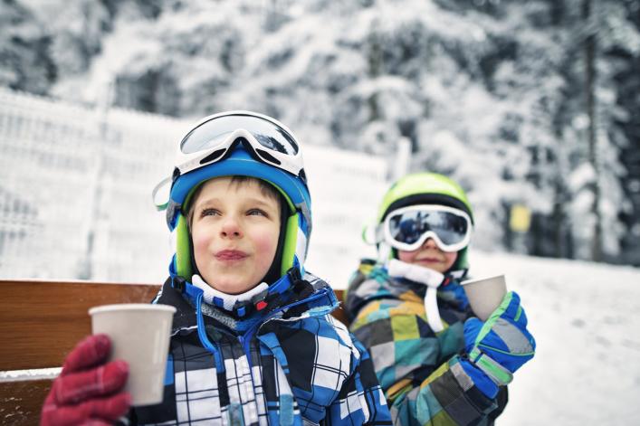 Fröhliche Jungen machen eine Skipause und trinken heissen Tee.