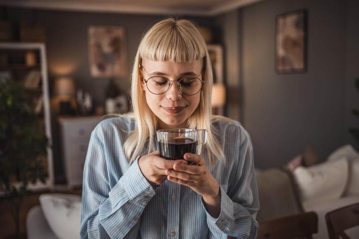 Junge Frau, die zu Hause einen schwarzen Kaffee geniesst