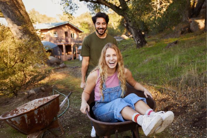 Fille-qui-se-fait-pousser-sur-une-brouette-par-un-ami-en-riant