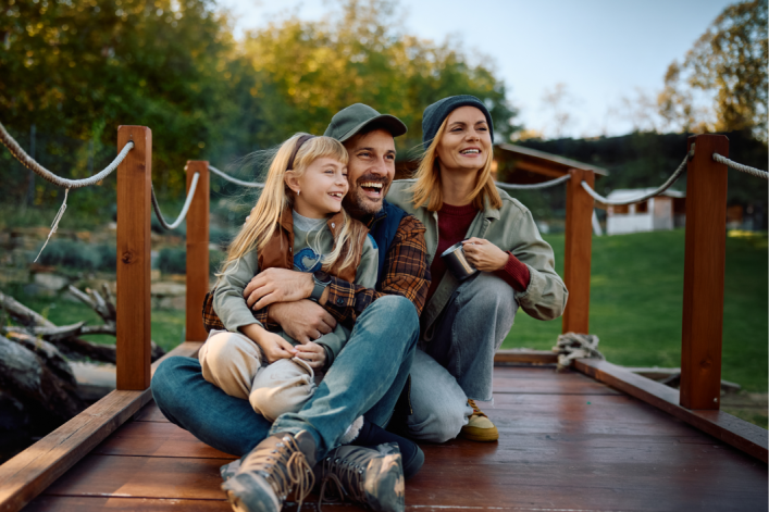 Familie sitzt auf einem Steeg und lacht