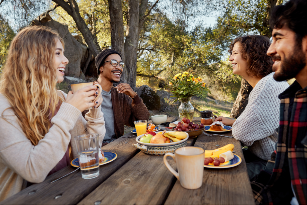 Freunde geniessen gemeinsam ein Frühstück im Freien an einem Holztisch 