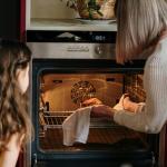 Mädchen und Großmutter beim Benutzen eines Ofens