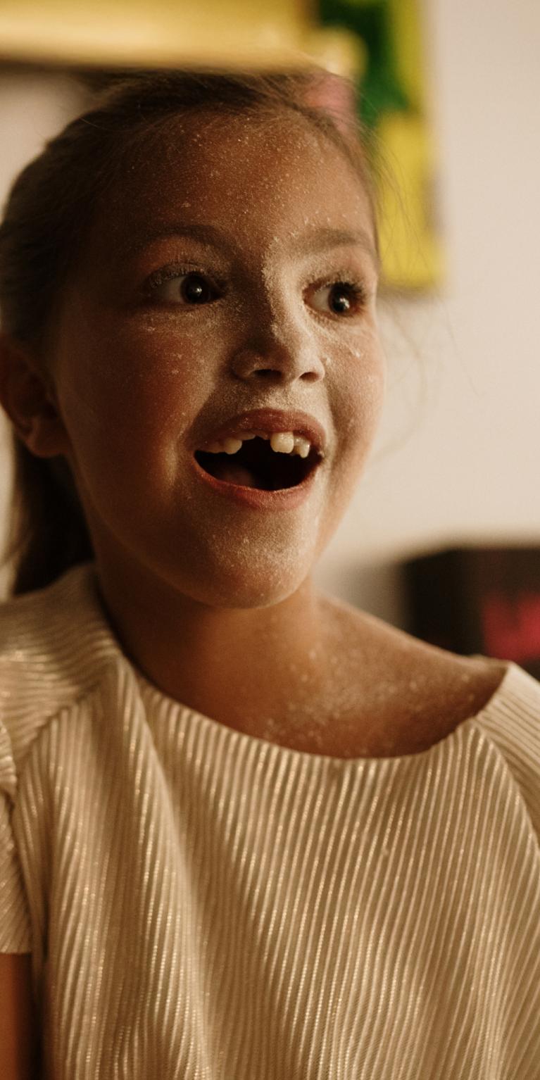 Kind lacht mit Mehl verschmiertem Gesicht