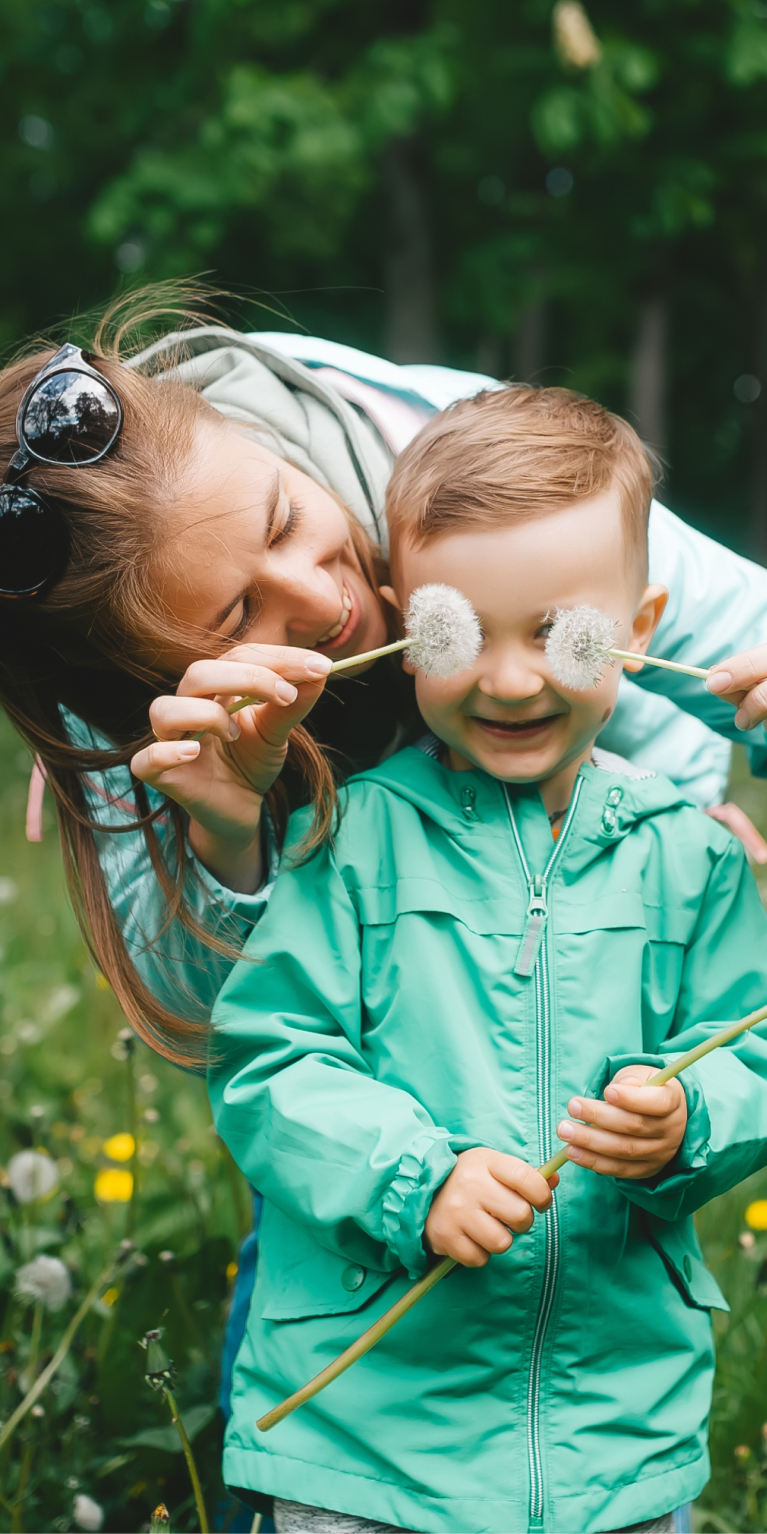 Erwachsener-und-kind-spielen-mit-löwenzahn
