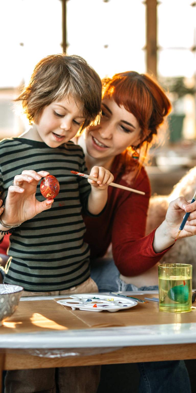 Eine Mutter und ihr Sohn bemalen kreativ Ostereier zu Hause