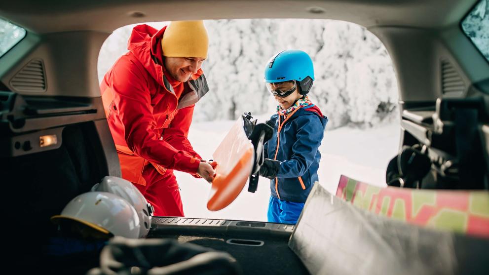 Vater und Sohn laden ihre Skis neben dem Auto aus und starten in den Skitag.