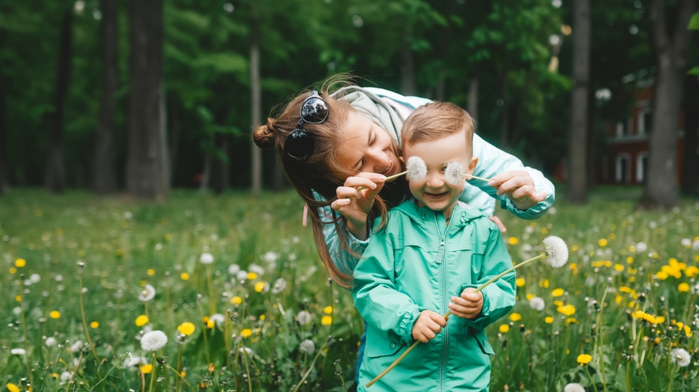 Erwachsener-und-kind-spielen-mit-löwenzahn