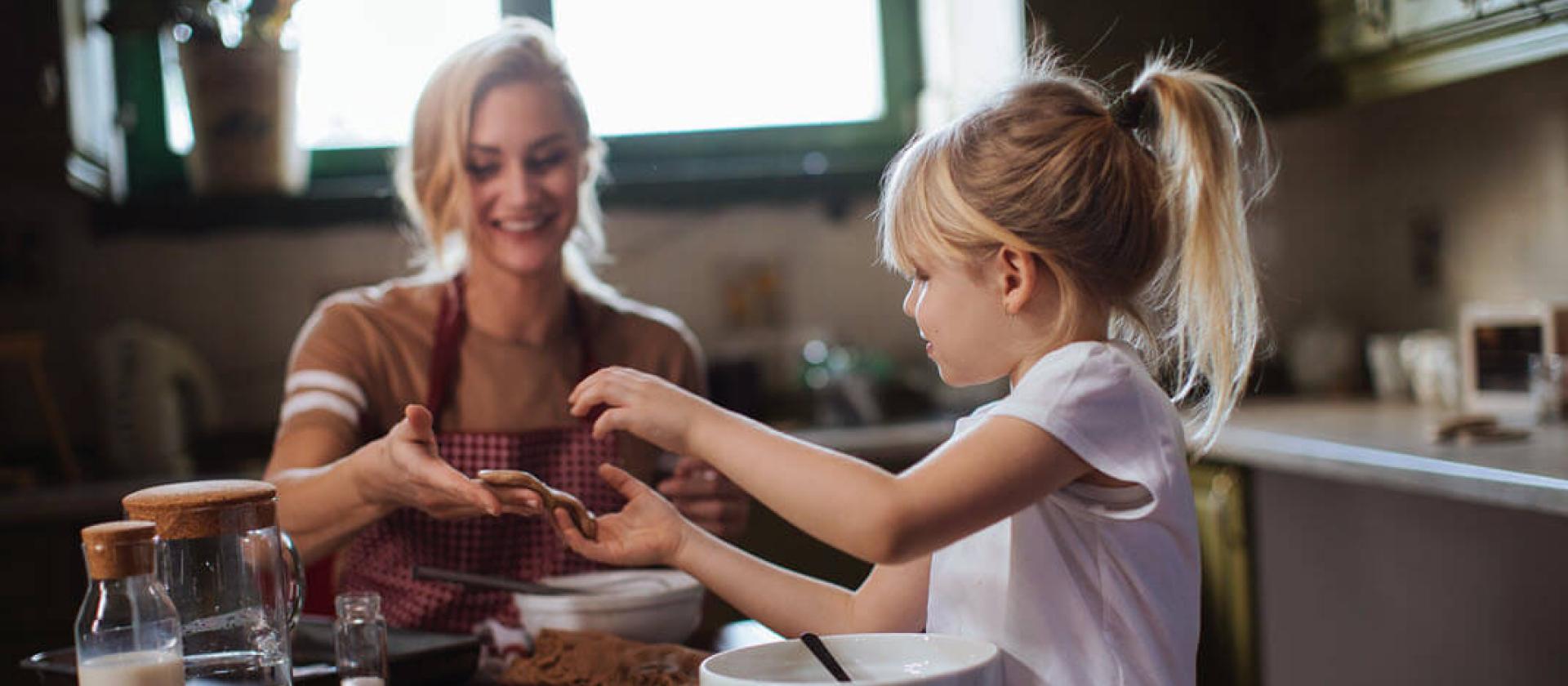 Mama und Tochter backen Weihnachtsgebäck in heller Küche.