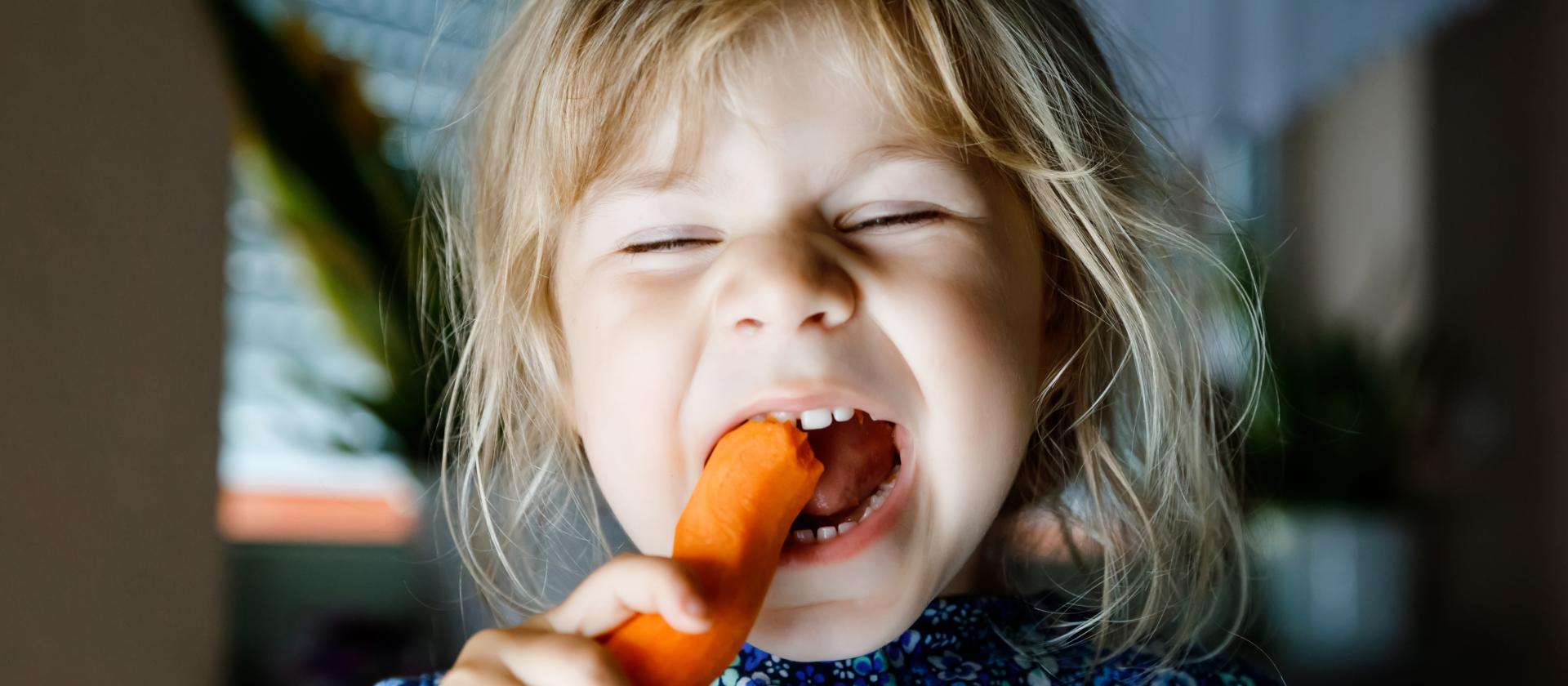 Kind isst eine Karotte