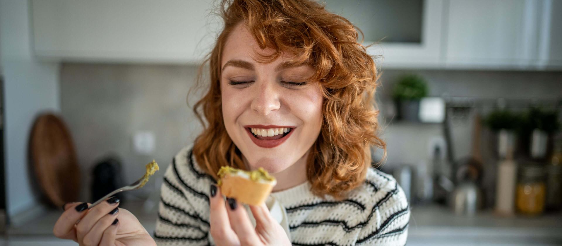 Junge Frau geniesst eine selbstgemachte Speise in der Küche