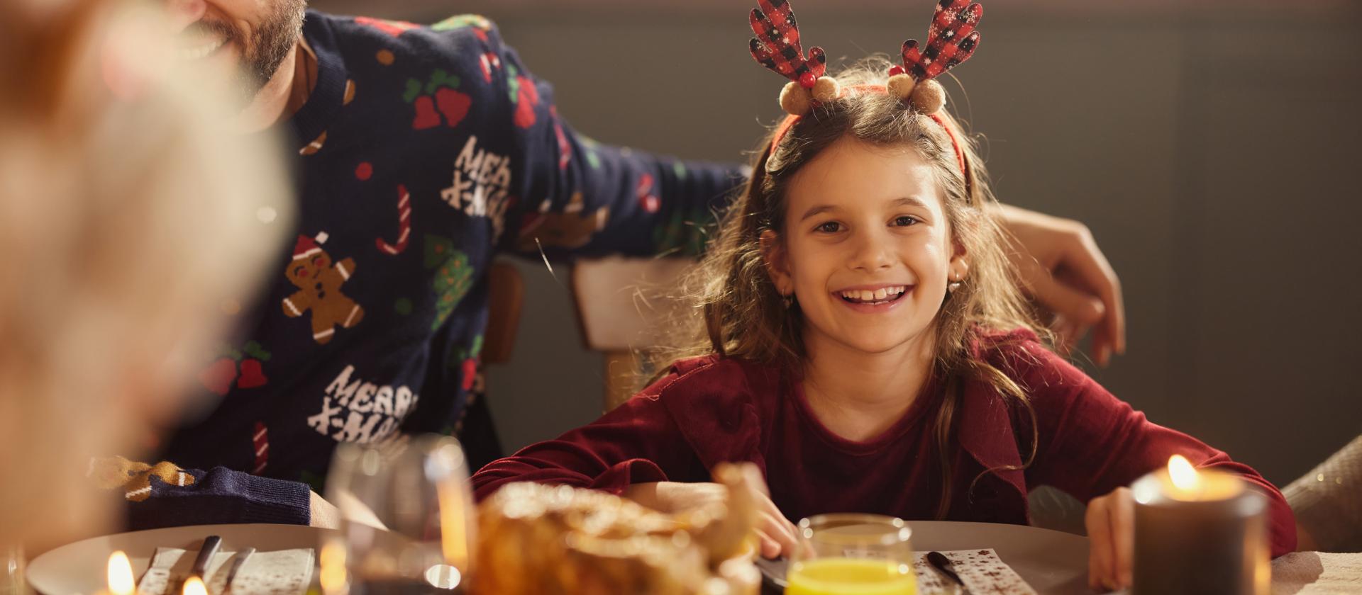 Festlich gekleidetes Mädchen am Esstisch mit Familie 