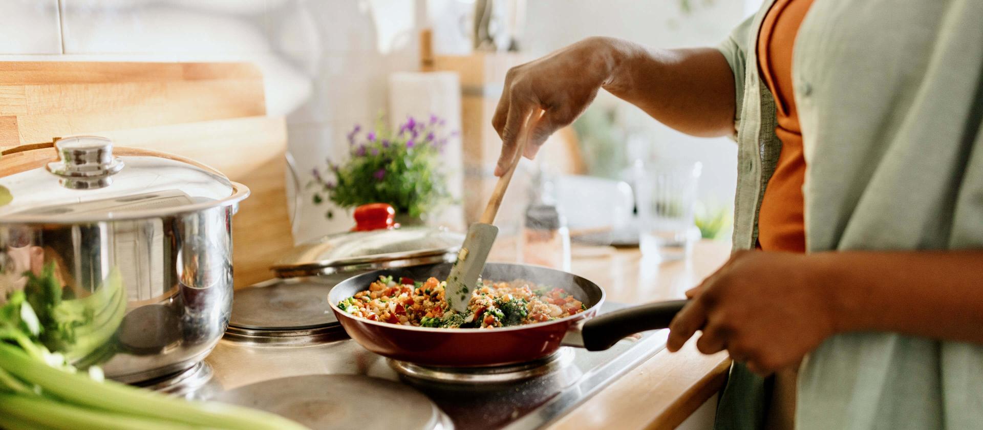 Femme préparant un mélange de légumes et de quinoa dans une poêle