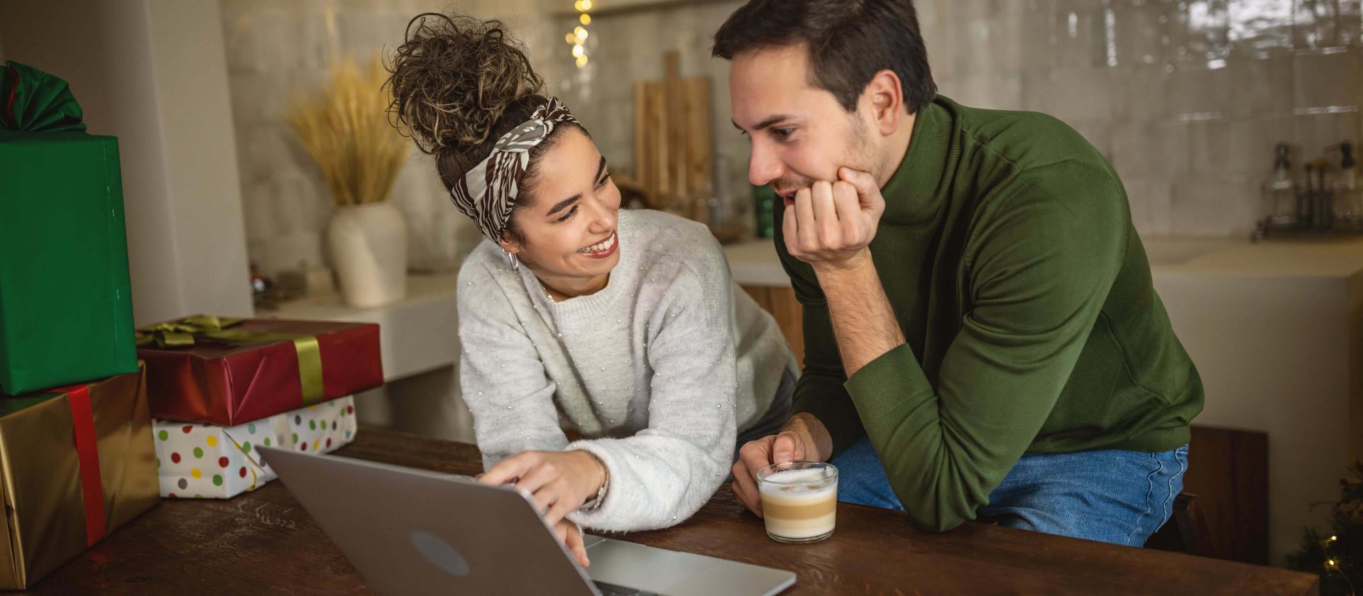 Jeune couple consultant des informations sur un ordinateur portable pendant les fêtes de Noël
