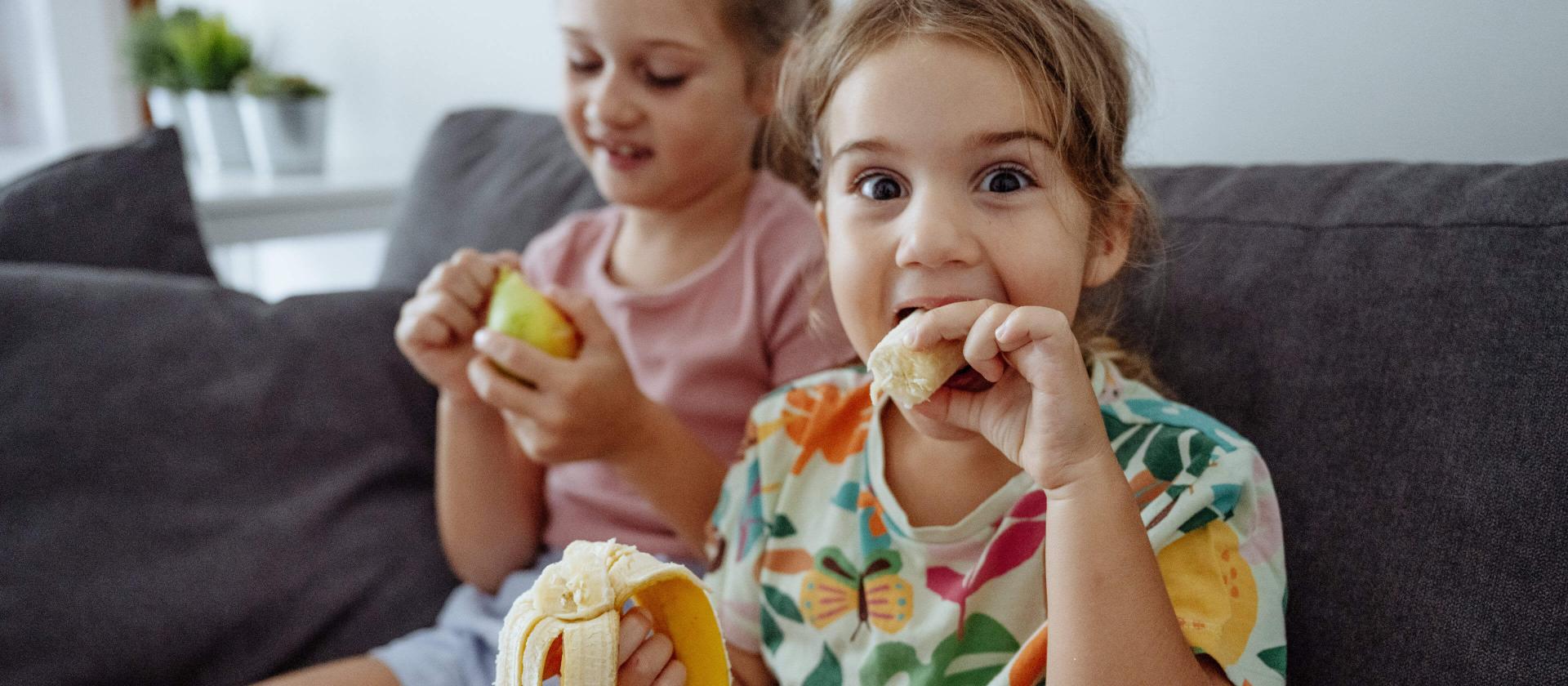 Jeunes filles partageant des fruits, l’une souriante avec une banane.