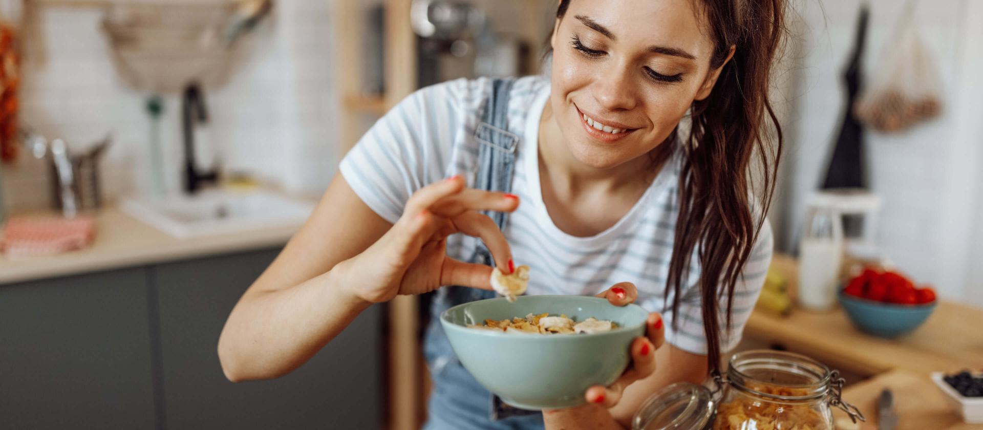 Jeune femme goûtant le petit-déjeuner qu'elle vient de préparer